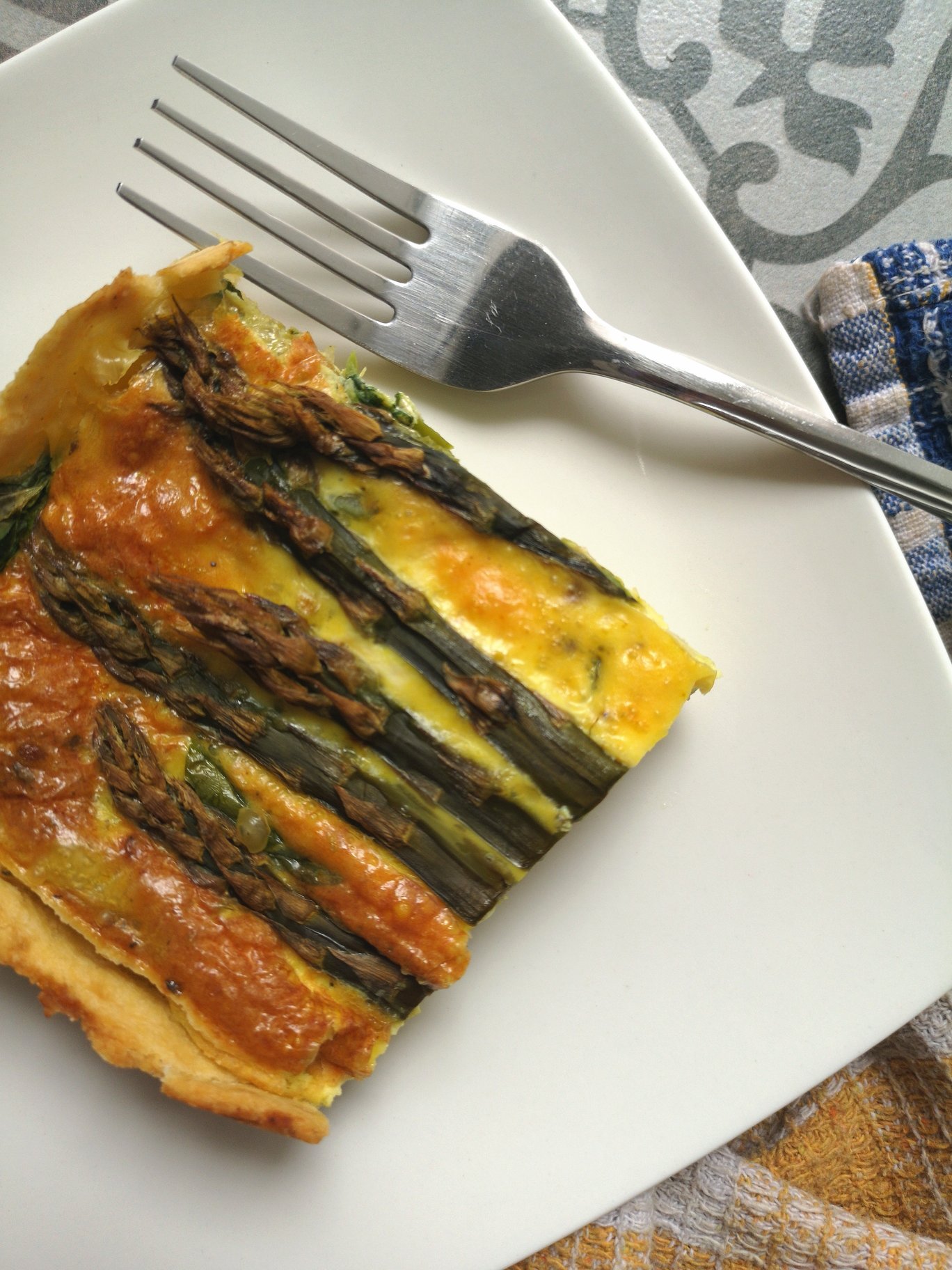 vegan spinach asparagus pie on a white plate with a fork