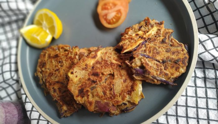 vegetable fritters on a blue plate with slices of tomato and lemon