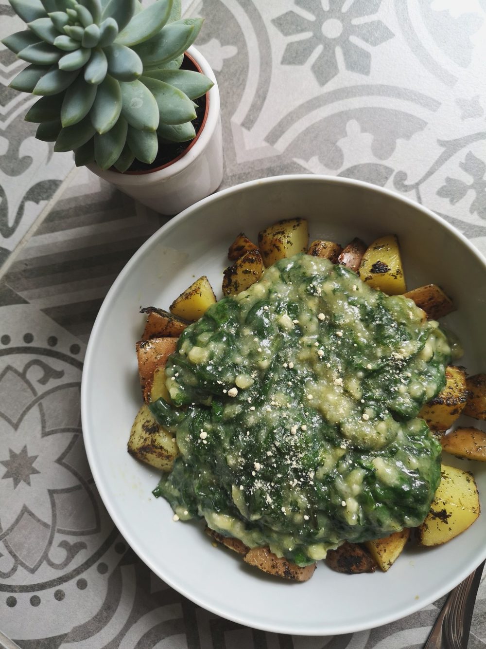 Vegan Creamed Spinach in a white bowl next to a succulent