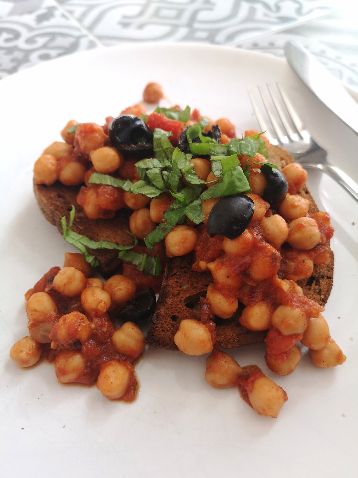 greek chickpeas on toast on a white plate with a fork