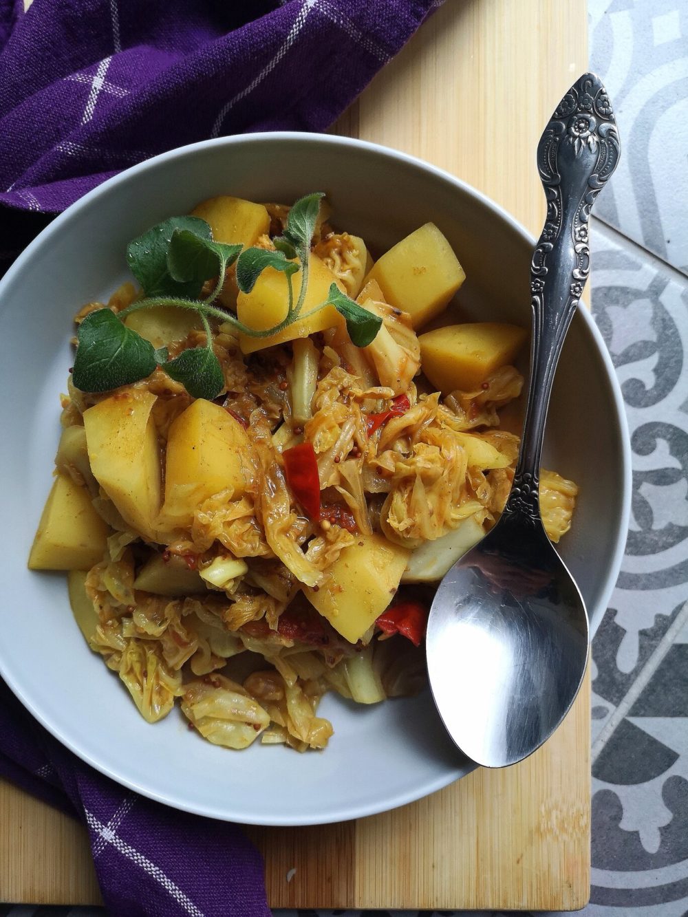 vegan cabbage potato sabji in a bowl with a spoon