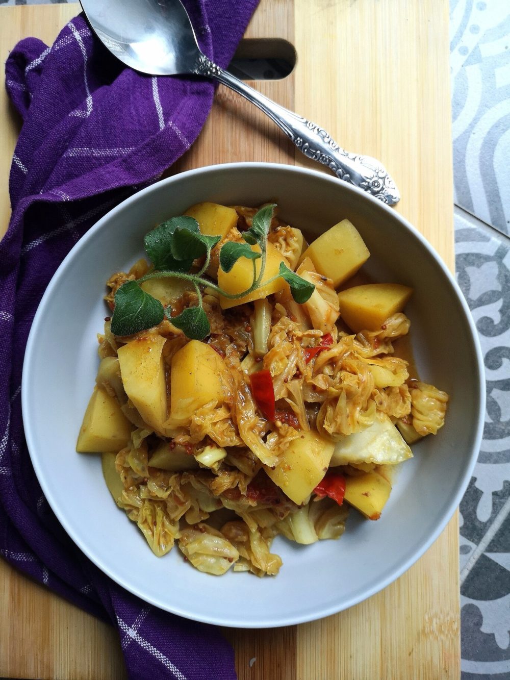 vegan cabbage potato sabji in a bowl with a spoon