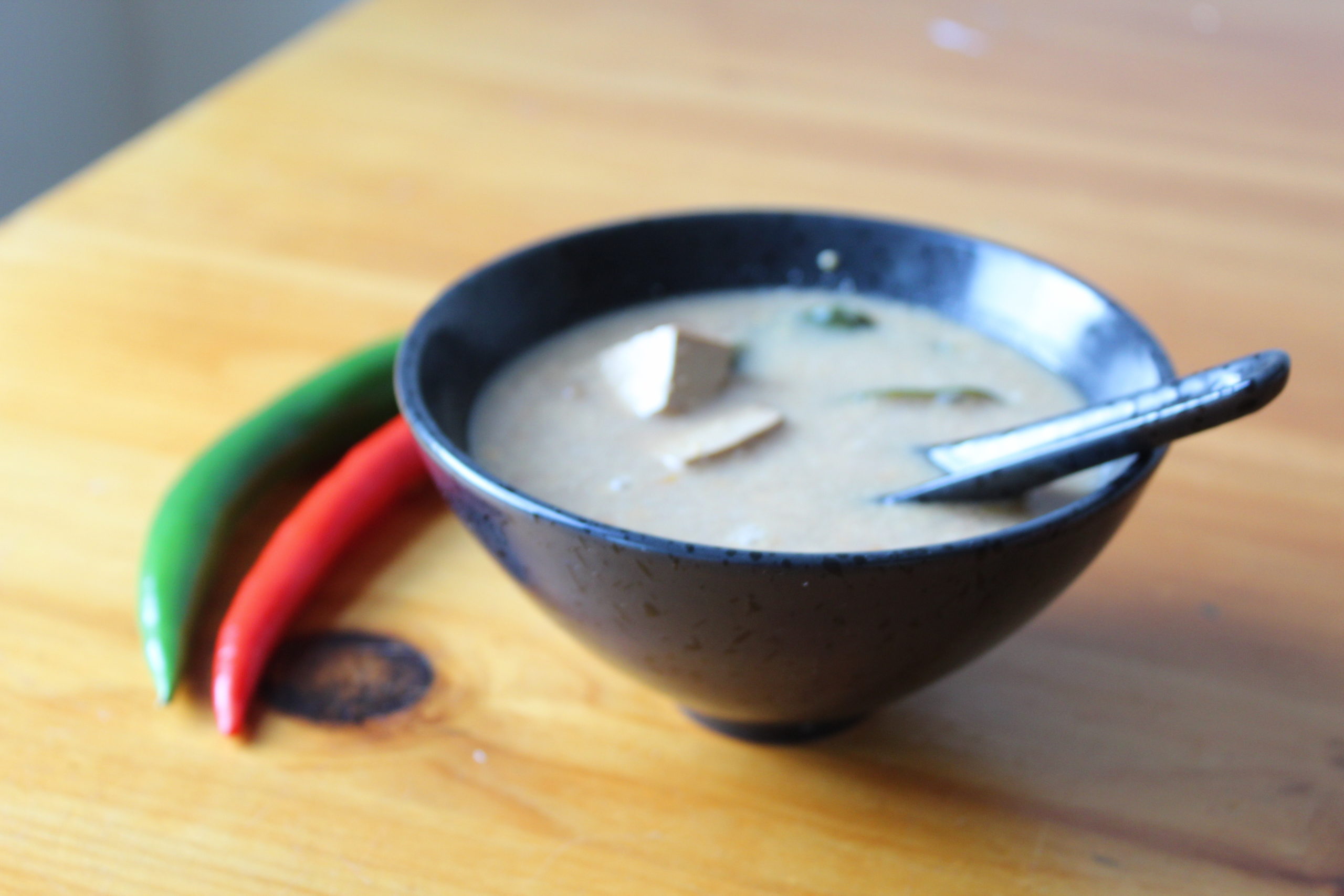 Tom Yum Thai Soup in a blue bowl on a wooden table top