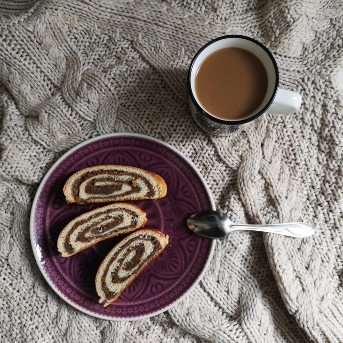 vegan bejgli; hungarian walnut roll on a plate with a cup of tea