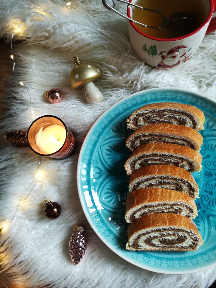 vegan bejgli; hungarian walnut roll on a blue plate with a cup of tea