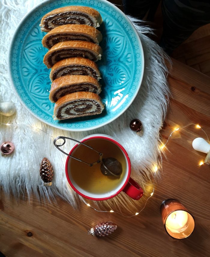 vegan bejgli; hungarian walnut roll on a blue plate with a cup of tea