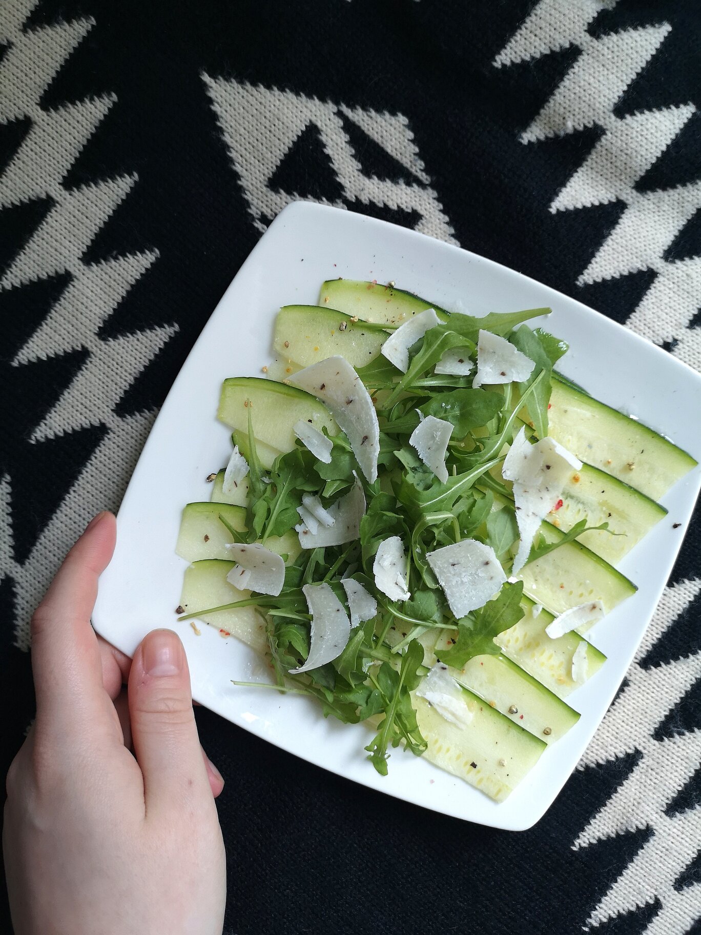 zucchini carpaccio salad with vegan truffle cheese on a white plate