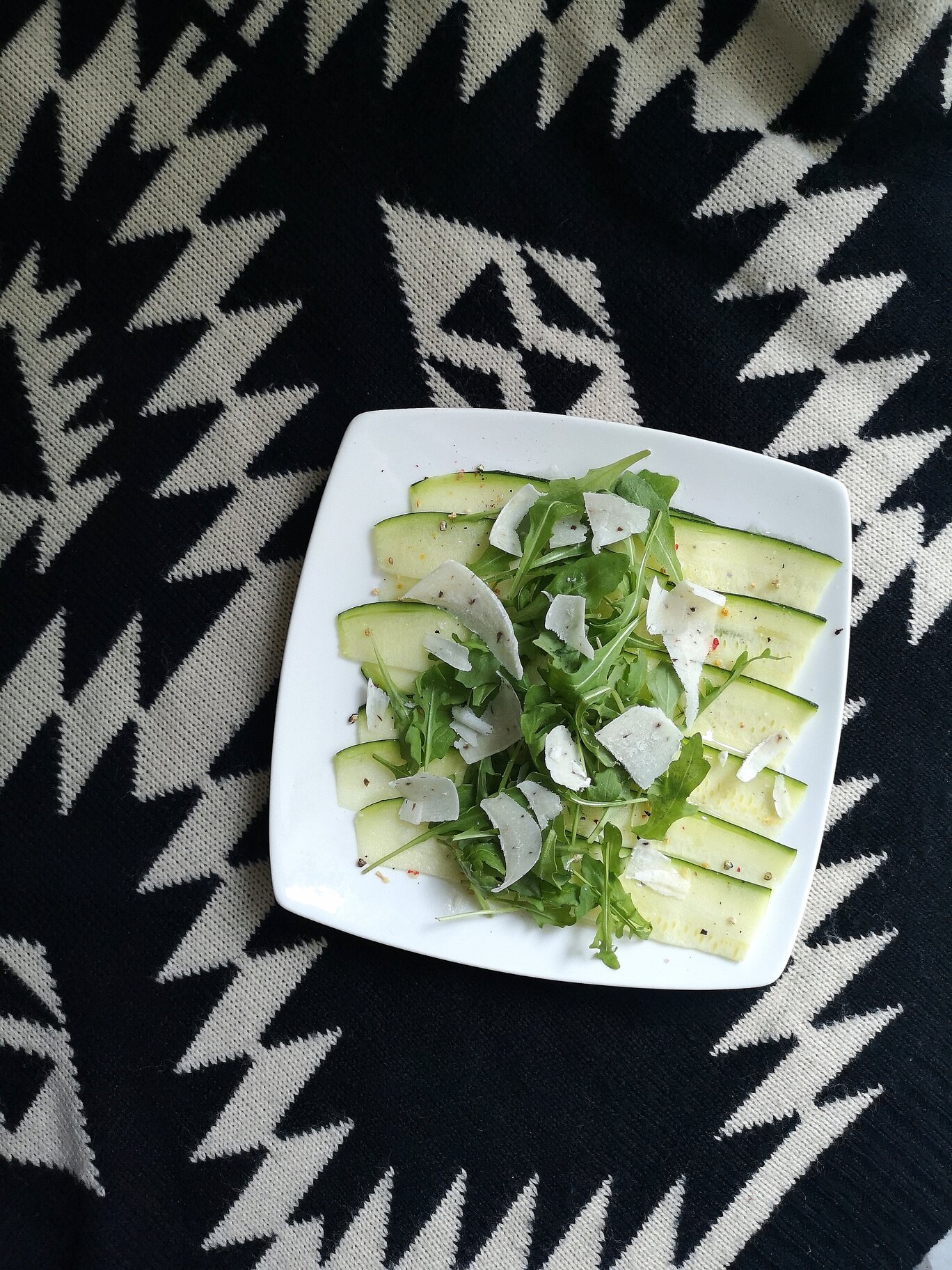 zucchini carpaccio salad with vegan truffle cheese on a white plate