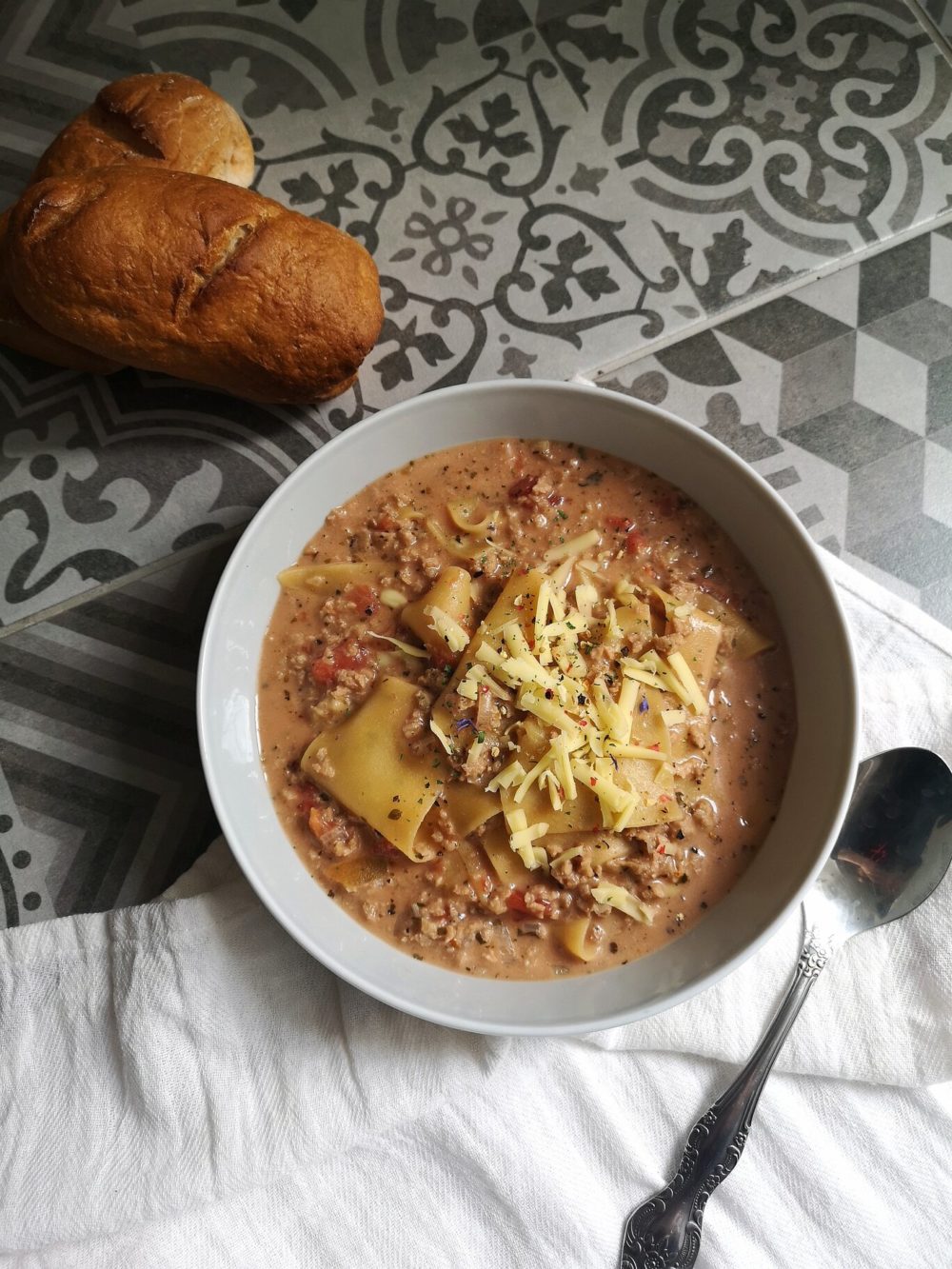 vegan lasagna soup with bread and a spoon