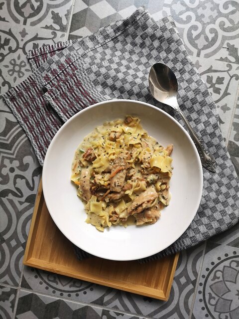 vegan lemon pasta in a white dish next to a silver spoon