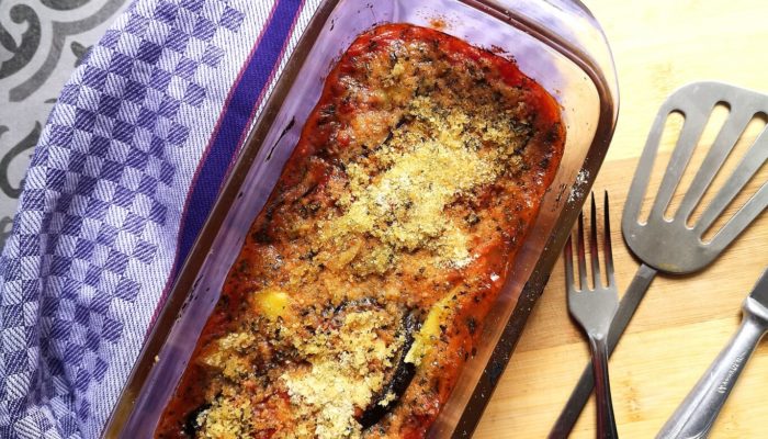 vegan eggplant parmesan in a baking dish next to silverware