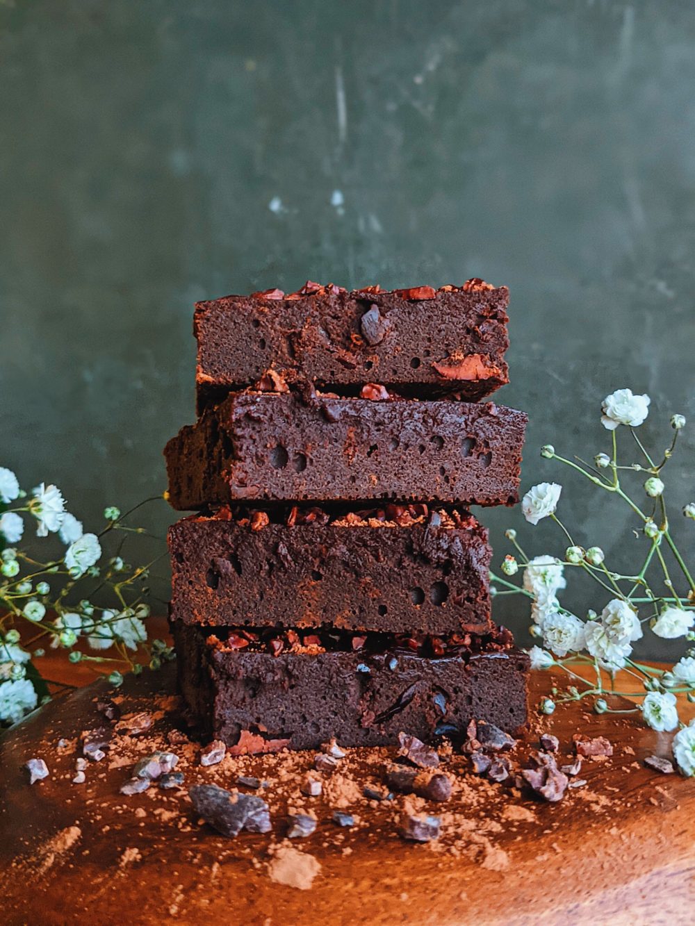 raw cacao brownies on a wooden table with white flowers