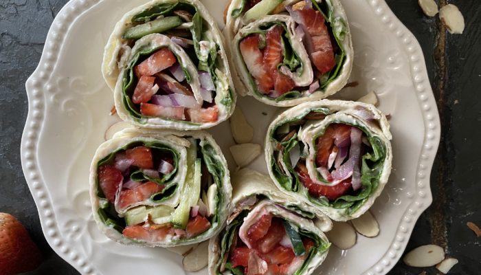 strawberry pinwheels on a white plate against a dark background