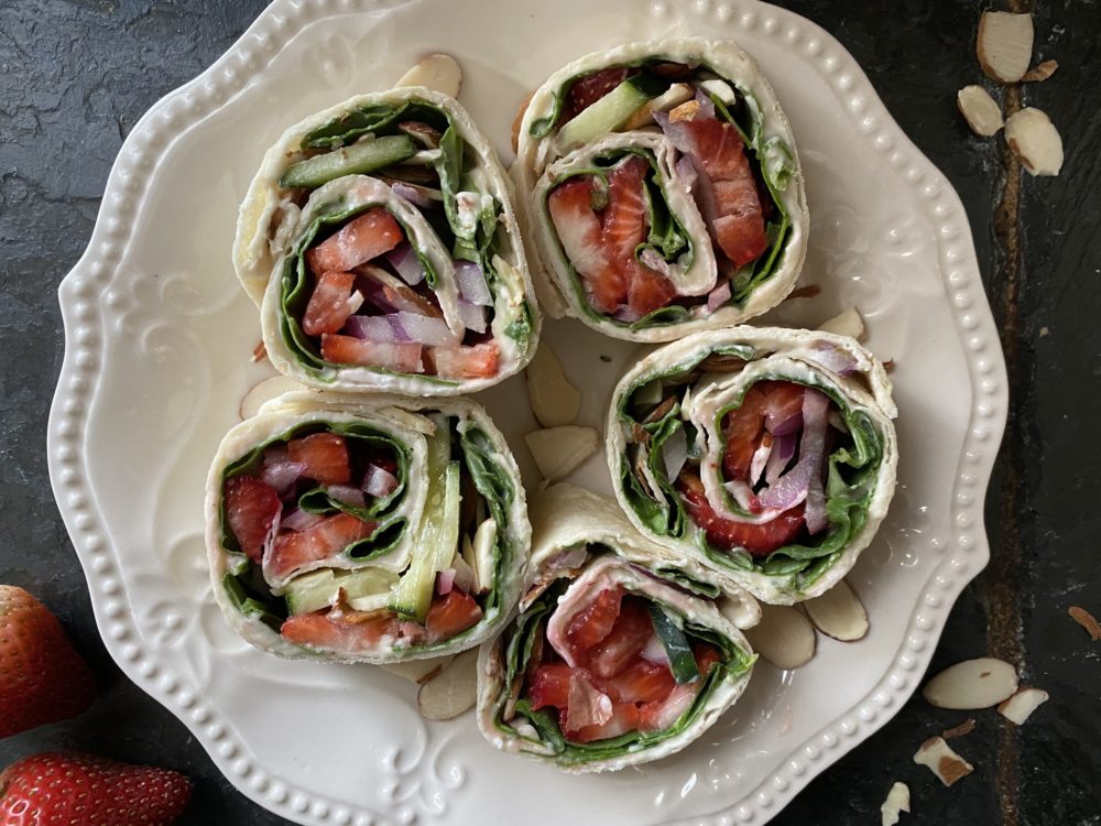 strawberry pinwheels on a white plate against a dark background