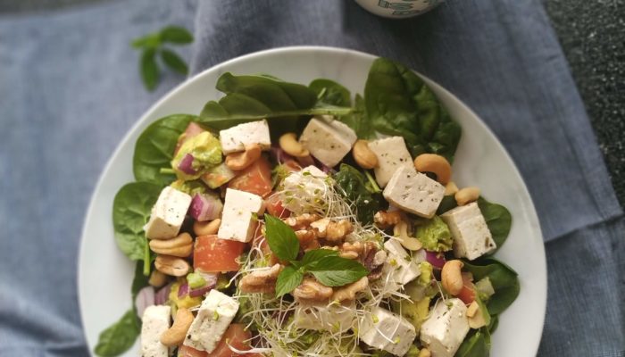 tofu feta salad on a white plate on a gray dish towel