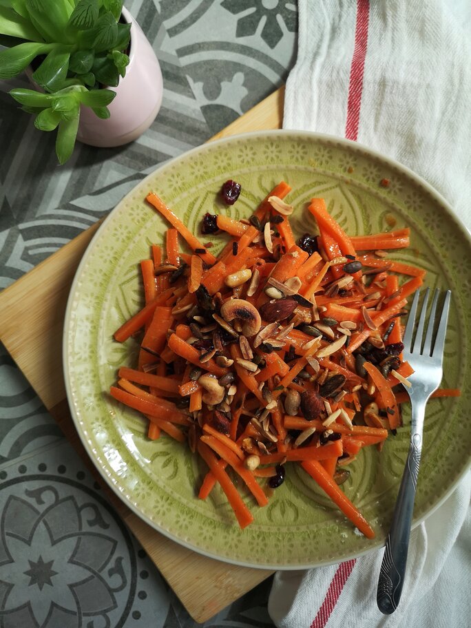 moroccan carrot salad on a green plate next to a plant