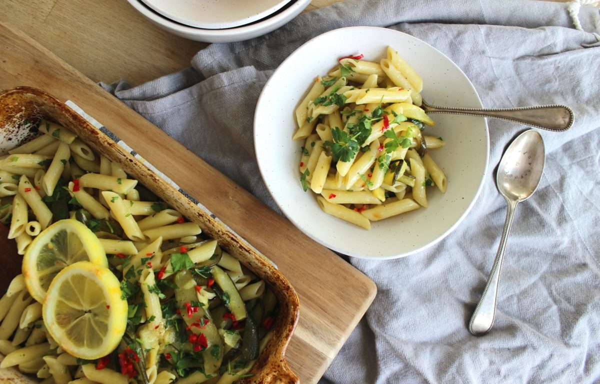 zucchini roasted lemon pasta in a white bowl next to a pan