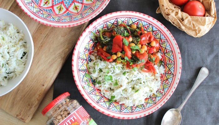 chickpea stew on a decorative plate next to a spoon on a black tablecloth