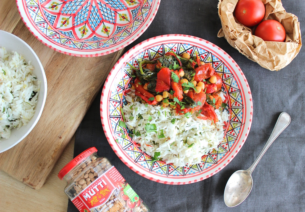 chickpea stew on a decorative plate next to a spoon on a black tablecloth