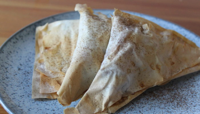 vegan apple pie turnovers on a speckled plate on a wooden table