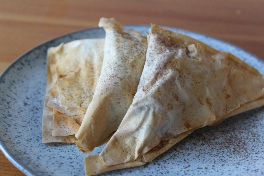 vegan apple pie turnovers on a speckled plate on a wooden table