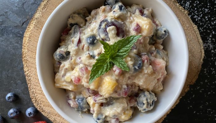 vegan ambrosia salad in a white bowl against a brown and black background