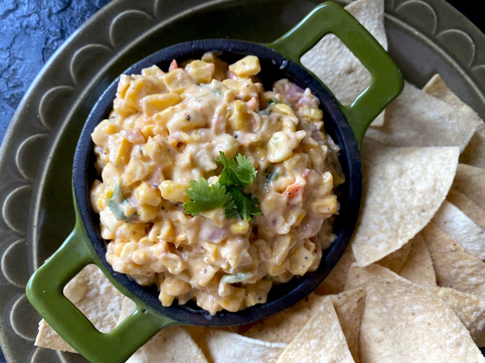 mexican corn dip in a dish next to tortilla chips