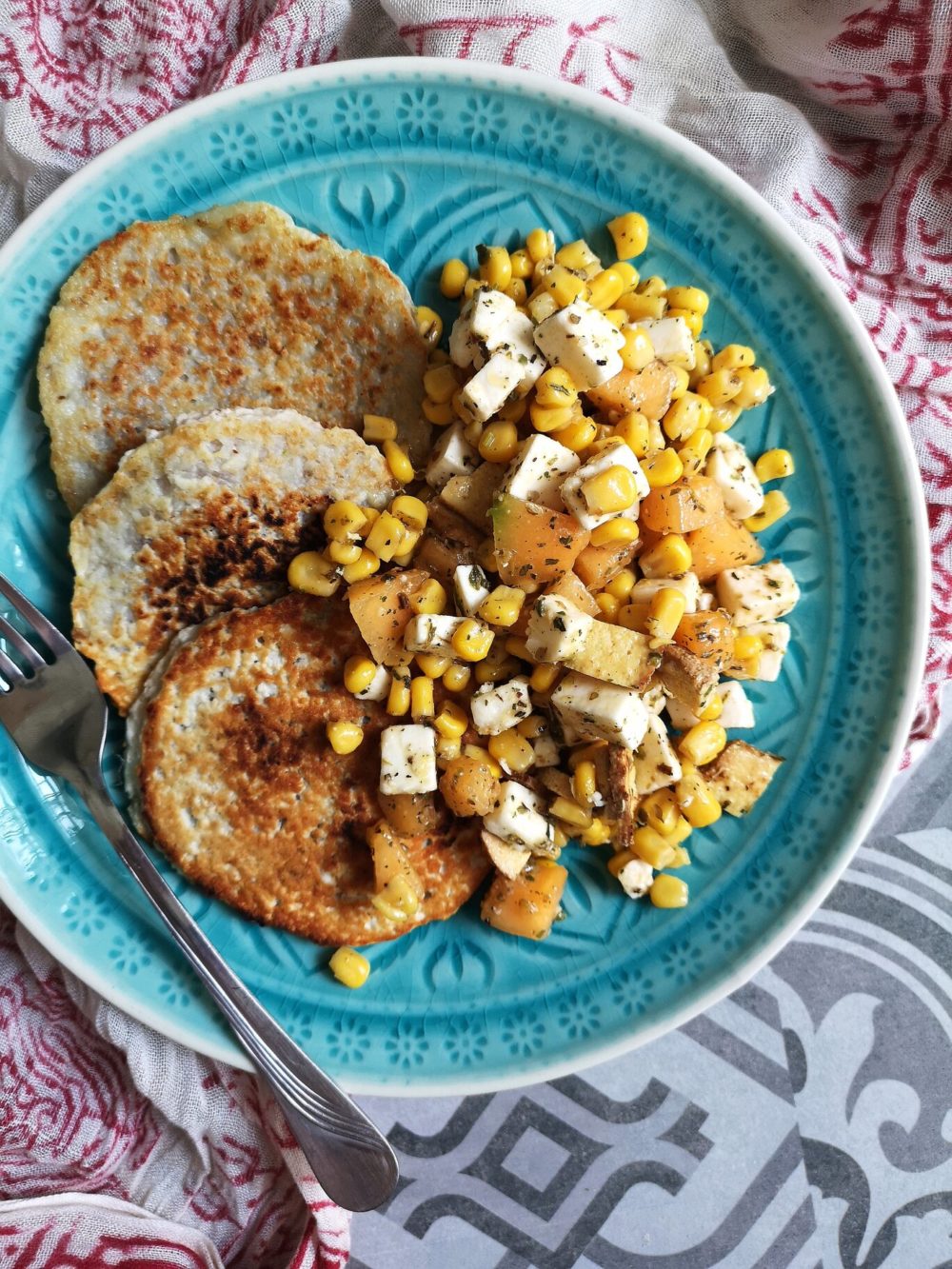 grilled melon and corn salad on a blue plate with a fork against a patterned background