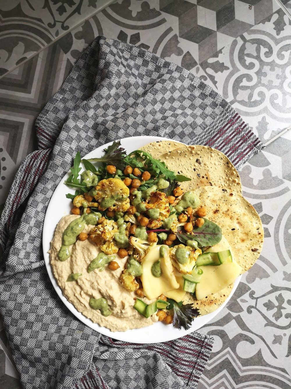 cauliflower shawarma on a white plate against a gray and white patterned background