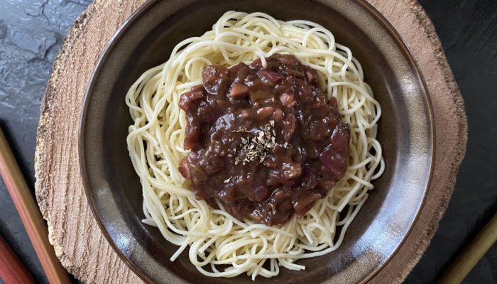 rhubarb pasta on a brown plate against a brown and black background