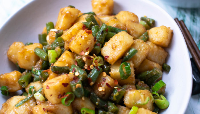 green beans and potatoes with garlic sauce in a white bowl