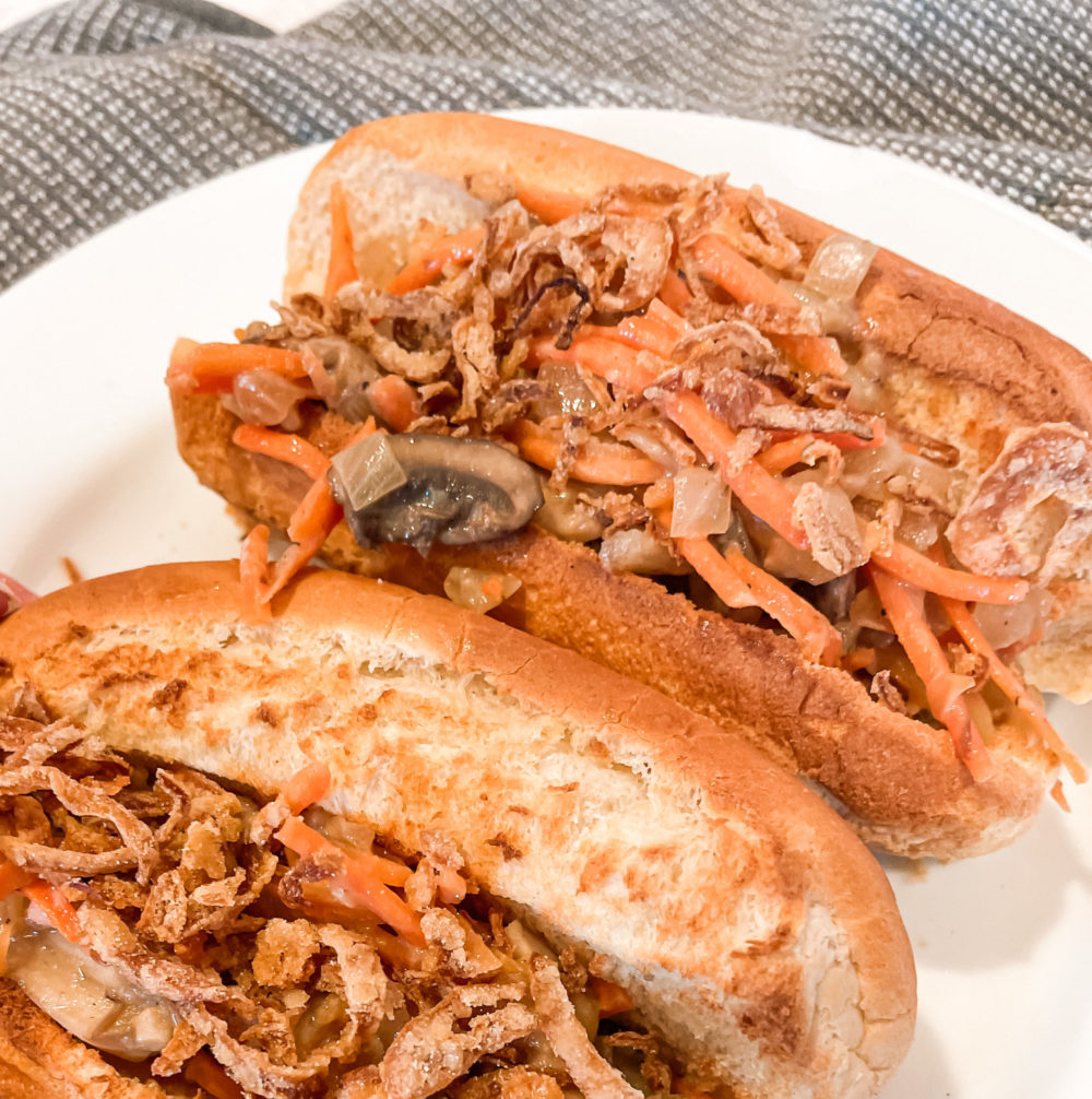 two hot dog buns with carrot mushroom slaw on a white plate