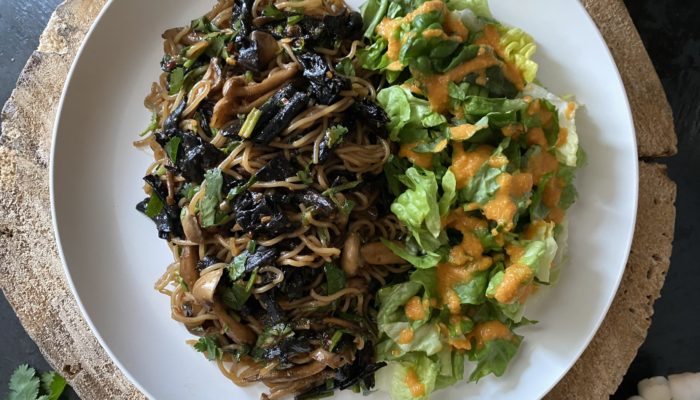 chili garlic ramen noodles on a white plate with brown and black background