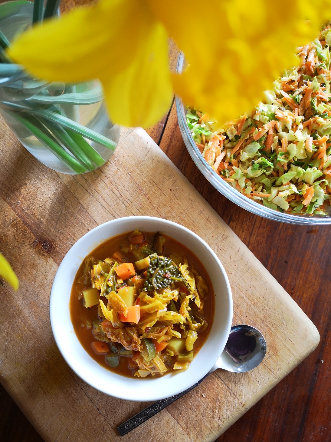 vegan spring garden subji in a white dish next to flowers