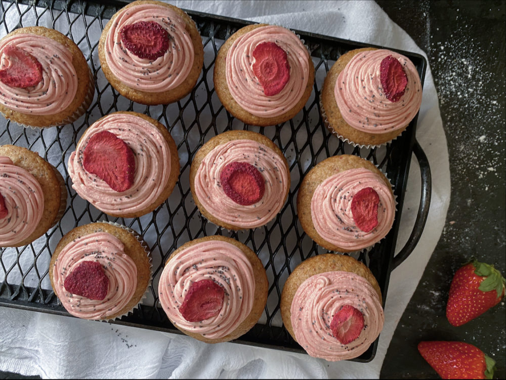 vegan strawberry poppy cupcakes on a black cooling rack