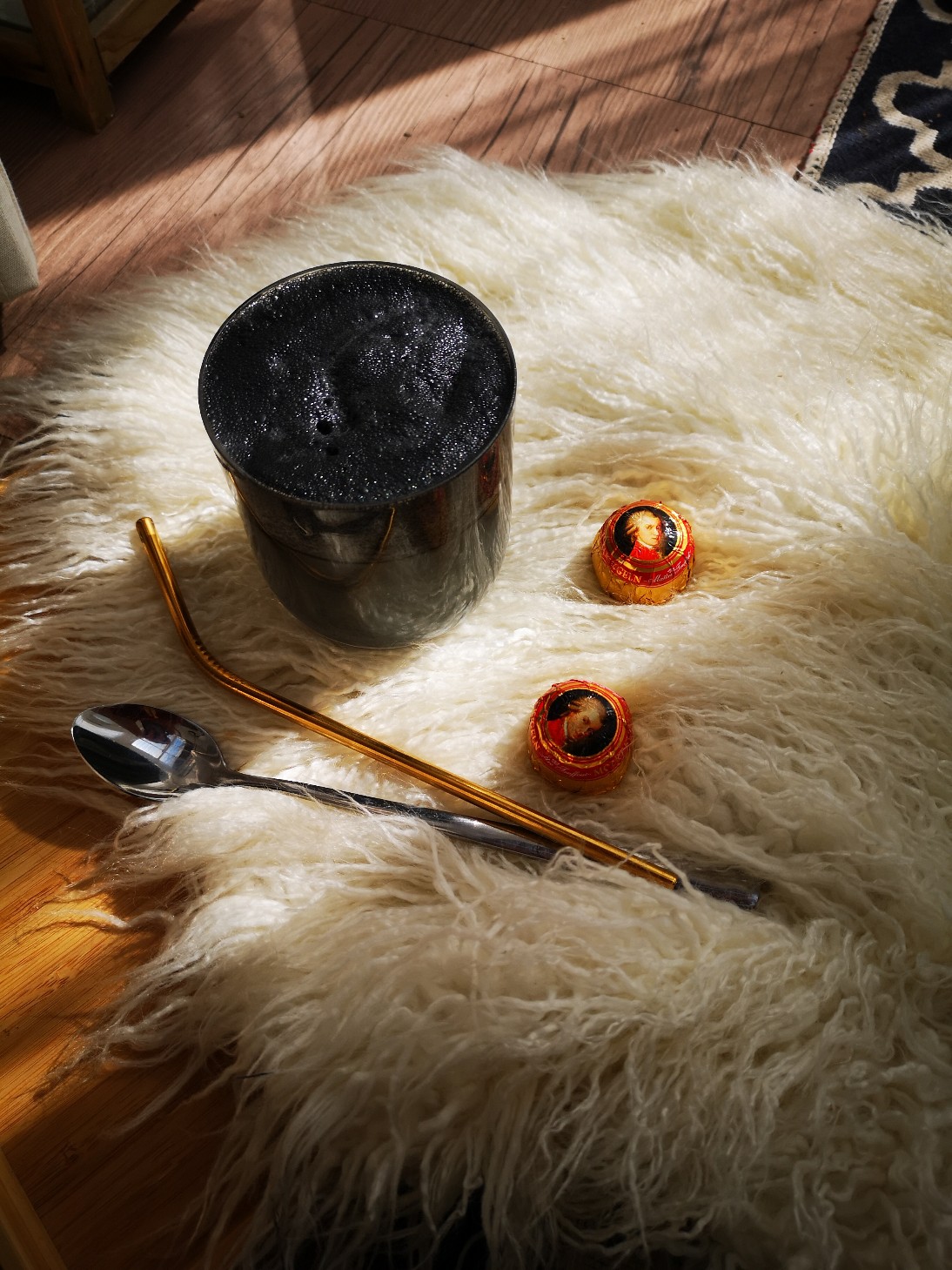 a charcoal drink sitting in the sunlight on a white fibrous rug