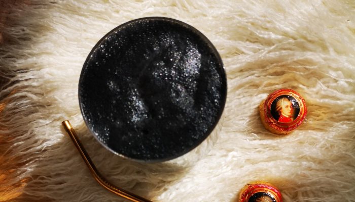 a charcoal drink sitting in the sunlight on a white fibrous rug