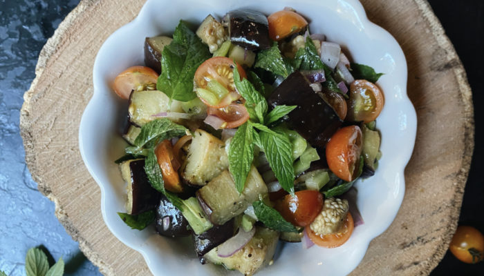 roasted eggplant salad in a white dish against a brown and black background