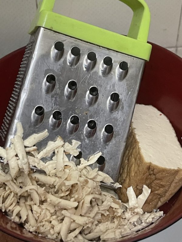 shredded tofu in a bown with a grater