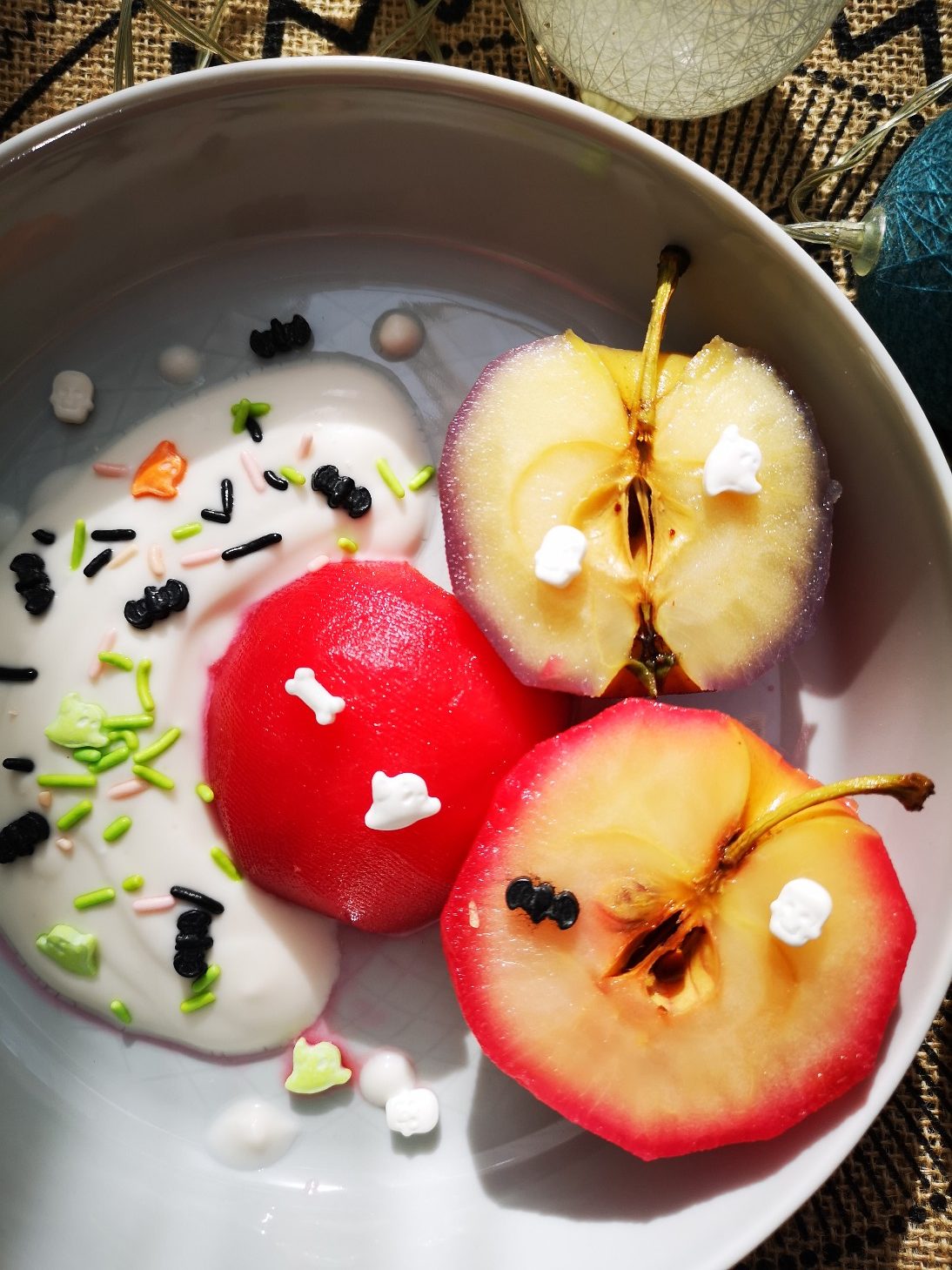 poached apples and sprinkles in a white bowl with decorations in the background