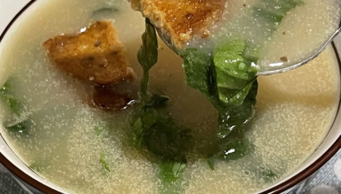 a spoonful of vegan caldo verde soup in front of a soup bowl