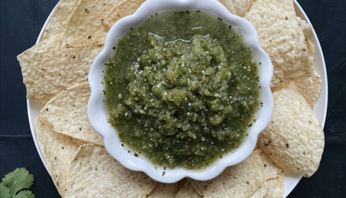 classic salsa verde and chips against a dark background