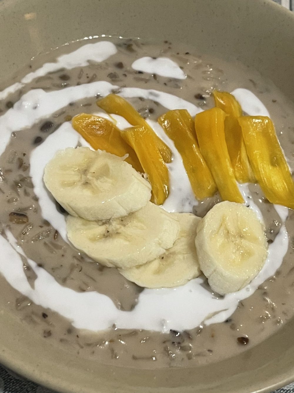 finished mung bean pudding with banana slices, coconut drizzle, and yellow fruit slices.