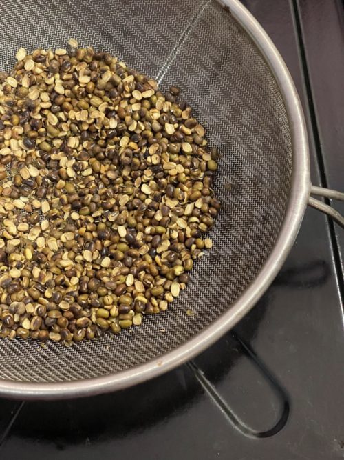 Mung beans in a sifter against a dark background