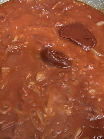 tomato sauce with tomato paste on the surface, cooking in a steel pan