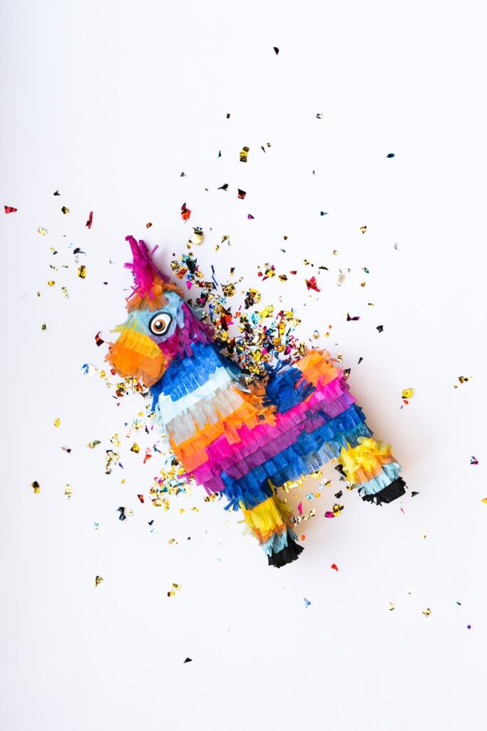 a colorful pinata is lying on a white floor with confetti spilling out of it.