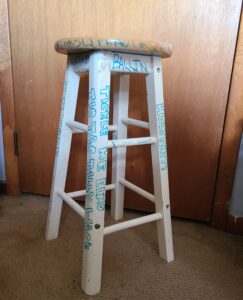 a wooden stool with colorful writing on its legs