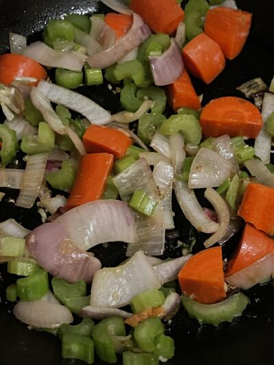 sautéed onions, celery, and carrots in a pan.