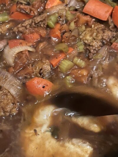 stirring a boiling pot of vegan beef stew.