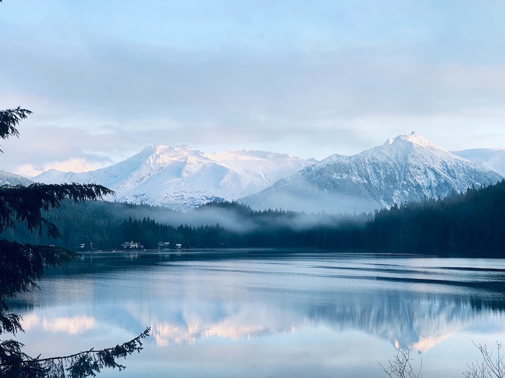 snow-capped mountains in the distance and a beautiful blue lake in the foreground in Alaska.